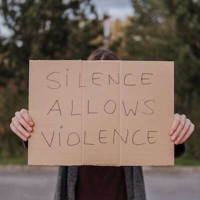Pappschild mit Aufschrift "SILENCE ALLOWS VIOLENCE"